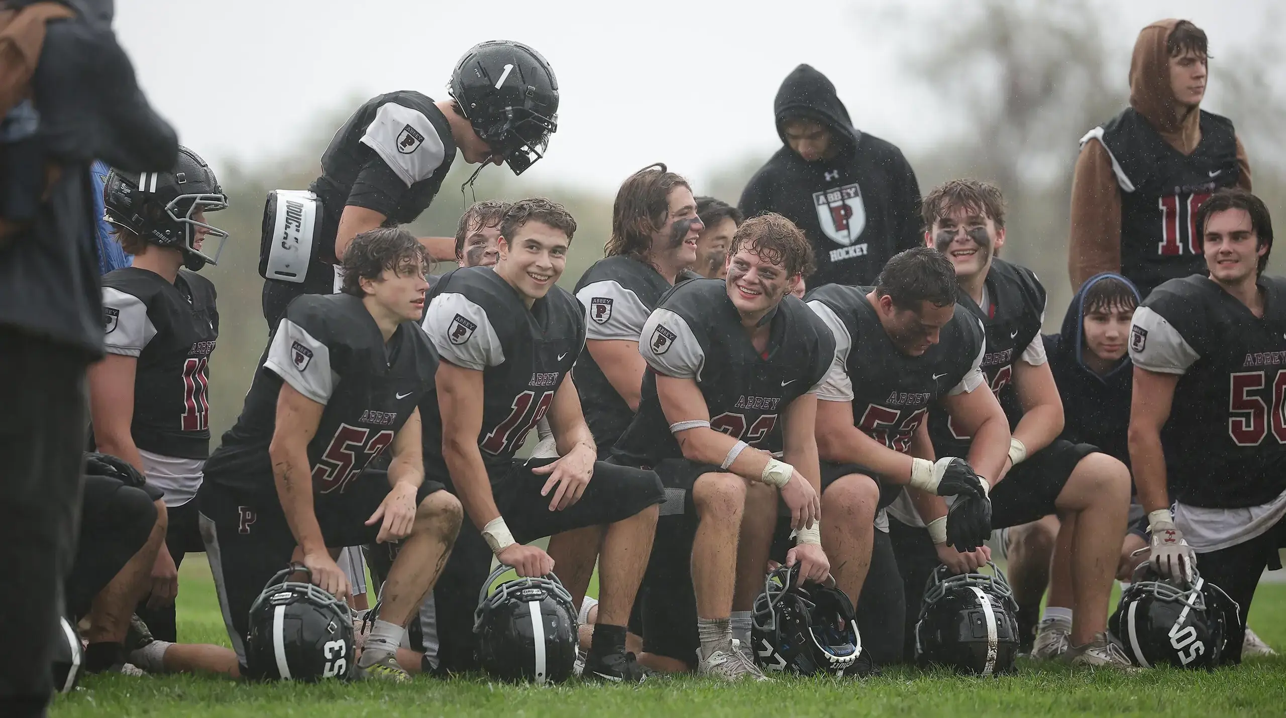 Football players smiling and taking a break on the field.