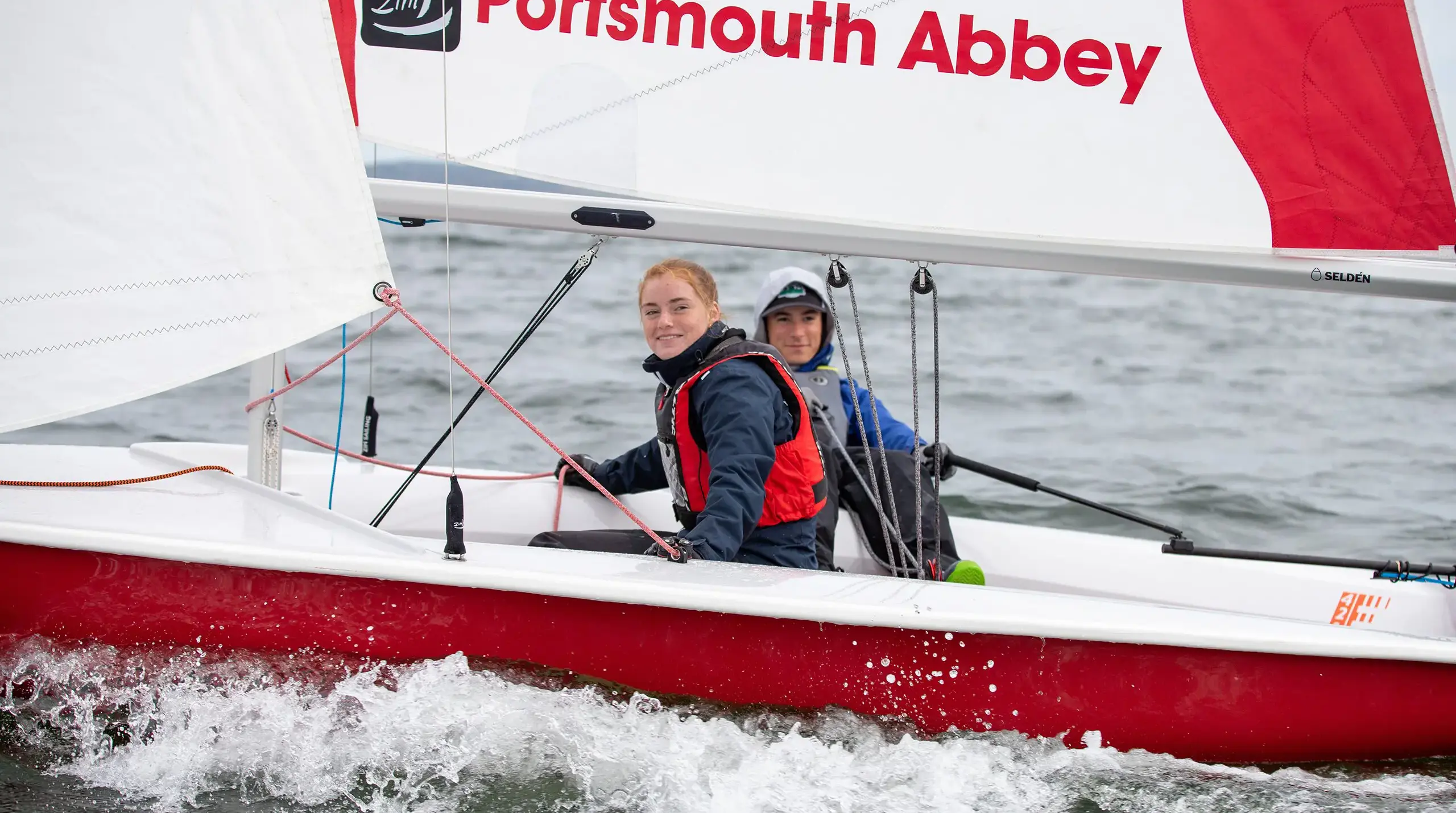 Two students sailing and looking at the camera.