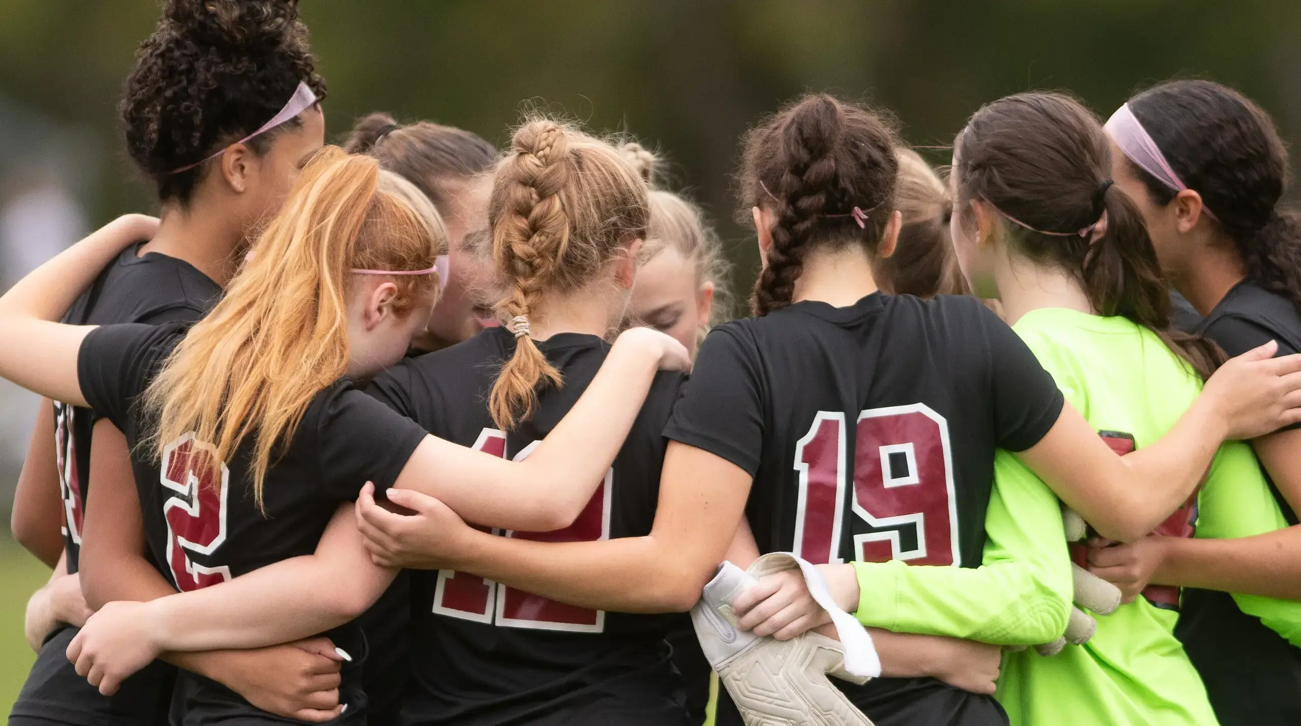 Girls on the field in a huddle.